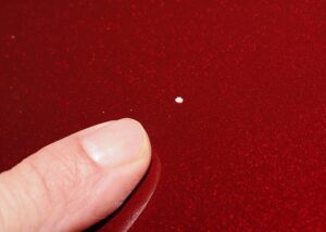 Chip repair on red car hood with seamless paint touch-up